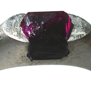 A close-up of a purple crystal on a silver ring