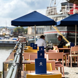 Harbourside view of Riverstation outdoor seating with blue parasols.