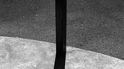 Black and white photo of a pole and its shadow.