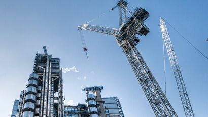 Upward angled shot on a contemporary skyscraper building on the left with a construction crane on the right of the image.