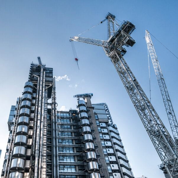 Upward angled shot on a contemporary skyscraper building on the left with a construction crane on the right of the image.