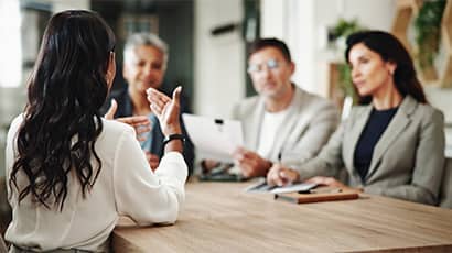 A meeting at the table in the office with 3 females and a male.