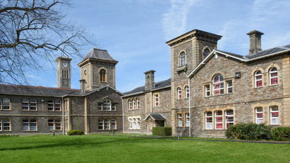 Exterior photograph of a building seen through the gardens and magnolia tree at UWE Bristol Glenside Campus.