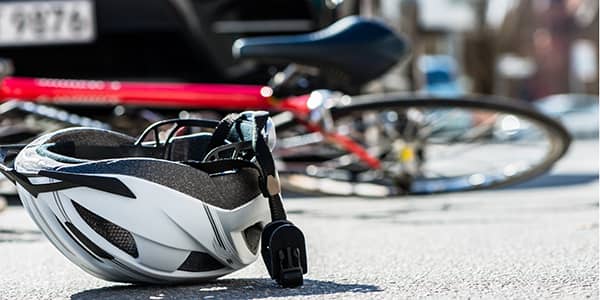 Close-up of a bicycling helmet fallen on the asphalt  next to a bicycle after car accident on the street.
