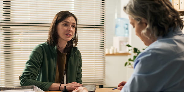 A middle-aged Caucasian female sitting opposite a female social worker in discussion. 