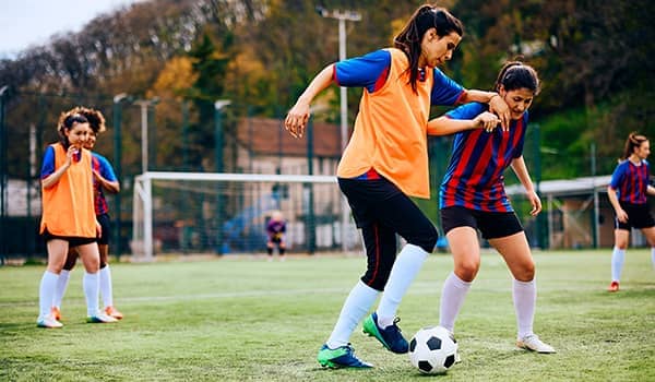 Female football players having sports training on a playing field.