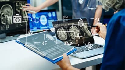 Medical professionals analysing scans on laptops with hologram overlays.