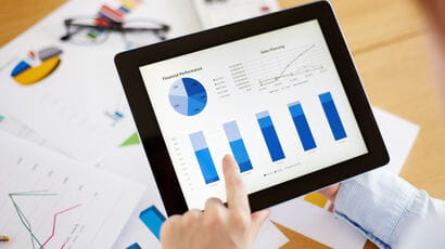 High angle cropped image of businesswoman scrutinizing financial performance on digital tablet at desk