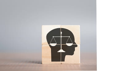 Four wooden cubes stacked together in a square formation to show the scales of justice within a head profile outline.