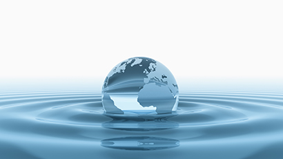 Image of Earth in the form of a water droplet situated on water surface creating a ripple effect.