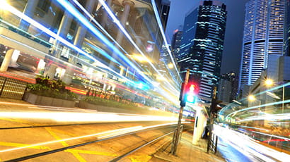 Dutch angled shot of an urban city scene at night with illuminated light trail against a backdrop of tall buildings.   