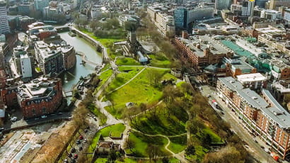 Aerial panoramic shot of Bristol City Centre with a river running alongside a large green park.