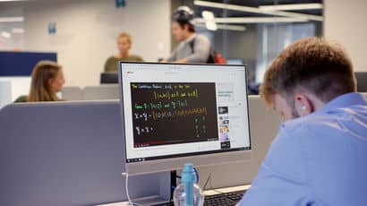 Maths student sits in front of a screen with algebra notation