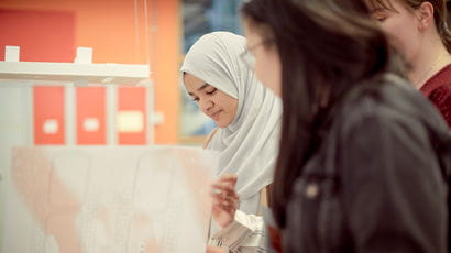 Students looking at designs printed on large-format paper.