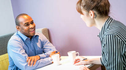 Two people talking in a break-out space.