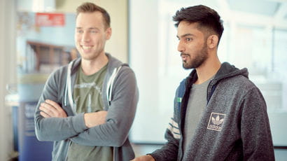 Two students smiling in a classroom. Two students smiling in a classroom.