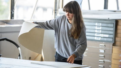 Person lifting a large sheet of paper.