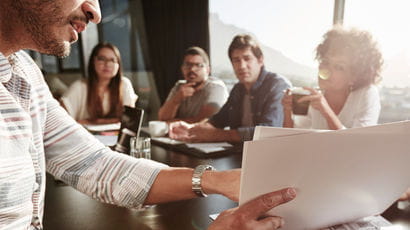 Group of people sat around a table discussing a document at a meeting.