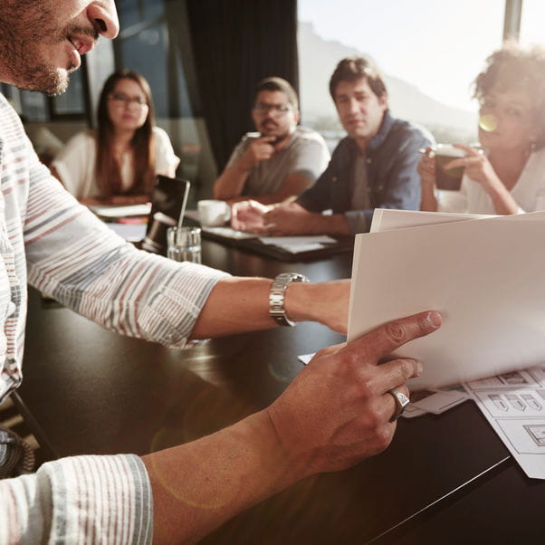 Group of people sat around a table discussing a document at a meeting.