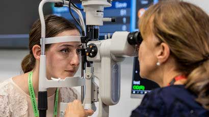 Optometrist using optometry equipment looking into a student's eye