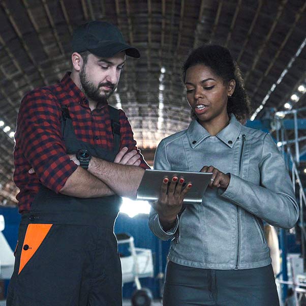 Woman talking with a man whilst looking at a tablet.