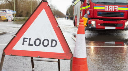 A flood sign with a fire engine behind.