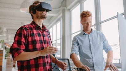 Young developer working on laptop and virtual reality glasses.