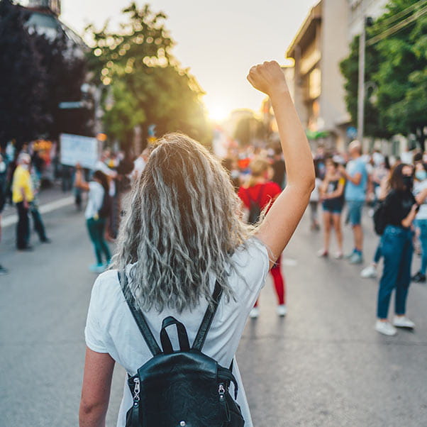 Person standing in the street with their arm raised in the air.
