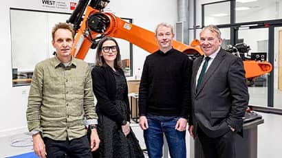 The Bridge Studio team standing in front of a large robotic arm