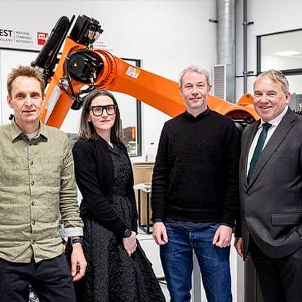 The Bridge Studio team standing in front of a large robotic arm