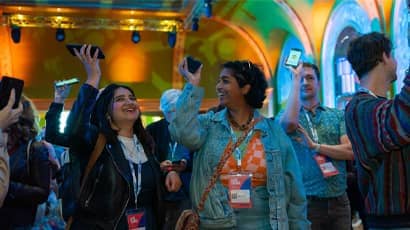 A crowd of people holding up their phones to take part in an Immersive Arts interactive exhibition