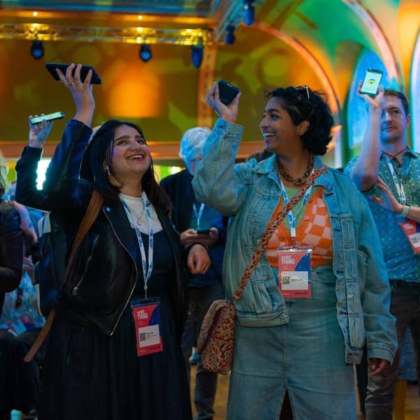 A crowd of people holding up their phones to take part in an Immersive Arts interactive exhibition