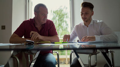 A student talking to a member of staff at a desk