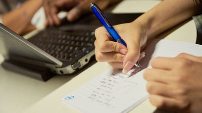 Hands writing with a pen on a piece of paper