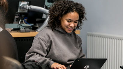 A student smiling down at a laptop
