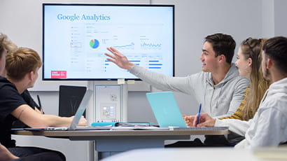 Group of students sitting around a table going through a presentation about google analytics