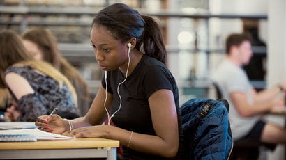 Student with headphones in writing on paper