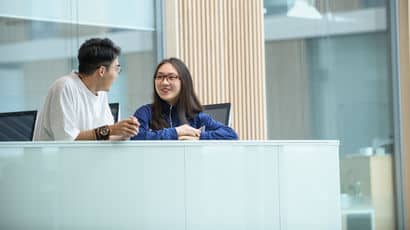 Two students sat behind a desk