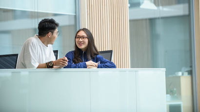 Two students sat behind a desk