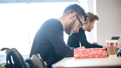 Student writing at a desk