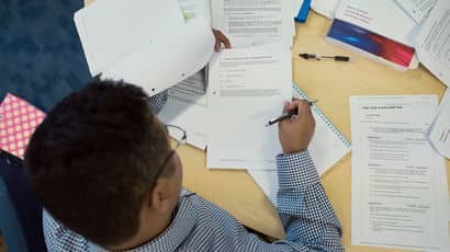 Aerial photograph of a student writing in an exam paper
