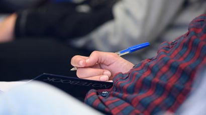 Closeup of student holding a pen.