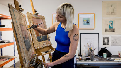 Artist painting on an easel in a studio.
