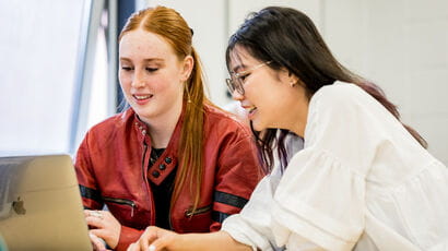 Two students using a laptop to study together.