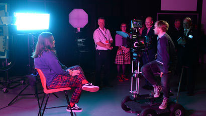 Student sat in front of a camera in a film studio.