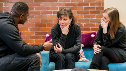 People offering support to someone sat on a sofa.