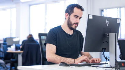 A postgraduate student using a computer in the library to study.