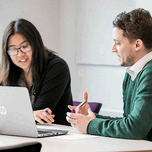 Two smartly dressed people sat at a laptop.