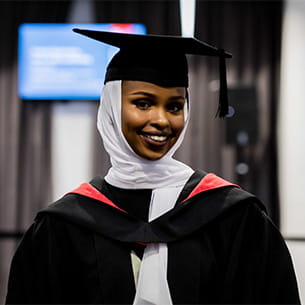 Profile of UWE Graduate smiling in cap and gown.