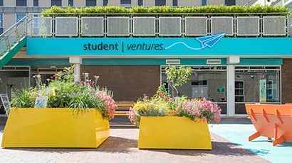 Exterior of the Student Ventures space entrance with bright orange concrete planters in front. 